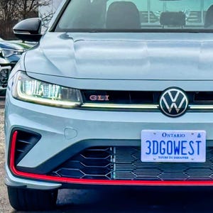 May include: A silver grey Volkswagen Golf GTI with a red accent on the front bumper. The car has a black grille and black headlights. The car has a licence plate that reads "3DGOWEST".