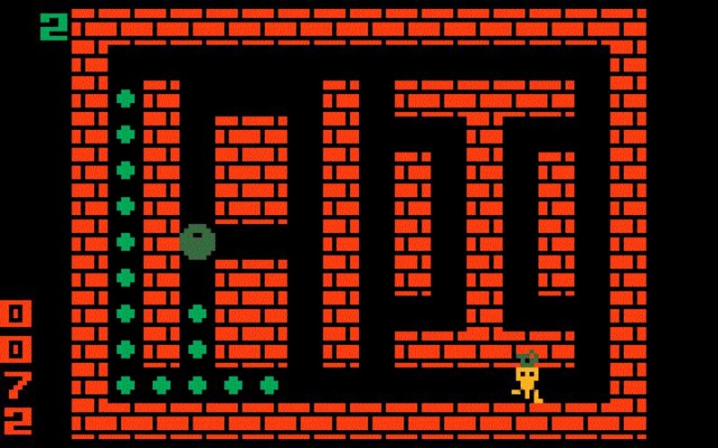 May include: Retro video game screen featuring a maze constructed of orange bricks. A small yellow character with a hat navigates the maze. Green dots and a green ball are also present. The game's score is displayed on the left side.