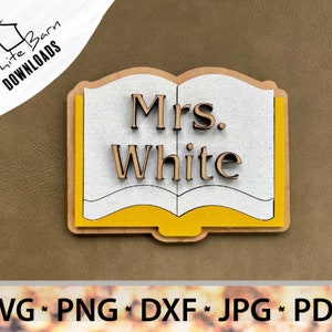 May include: A wooden cutout of an open book with the text "Mrs. White" in a brown font. The book is yellow and white.