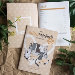 Könnte beinhalten: Ein beige-weißes Kätzchentagebuch mit einem Herz um den Titel "Unser Kittentagebuch" und einem Bild von Kätzchen, die mit Spielzeug spielen. Unter dem Titel steht der Text "Für einen Wurf". Das Cover enthält auch den Text "Ideal für 8 Kätzchen!"