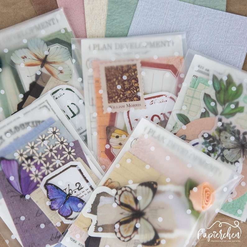 May include: Assortment of vintage-style paper ephemera and stickers in a clear plastic bag with white polka dots. The ephemera includes butterflies, flowers, and text that says "Plan Development" and "William Morris".