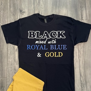 May include: A black t-shirt with the words "BLACK mixed with ROYAL BLUE & GOLD" in white, blue, and gold lettering. The shirt is folded over a yellow garment.