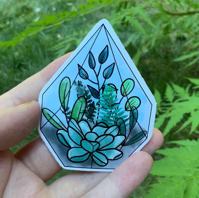 以下が含まれることがあります： 緑色の多肉植物、シダ、葉の茎など、さまざまな緑色の植物が入った幾何学的なテラリウムのステッカーです。