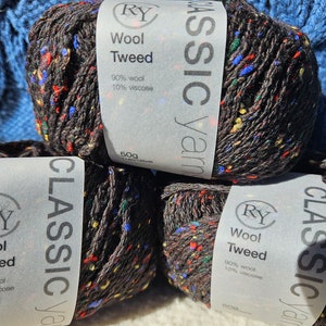 May include: Three skeins of dark brown tweed yarn with multicolored flecks of red, blue, yellow, and green. Each skein has a paper label reading RY Classic Yarns, Wool Tweed, 90% wool, 10% viscose, and 50g 125yds. The yarn has a textured appearance.