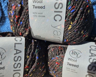 Può includere: Tre gomitoli di filato tweed marrone scuro con macchioline multicolori rosse, blu, gialle e verdi. Ogni etichetta riporta RY Classic Yarns, Wool Tweed, 90% lana, 10% viscosa e 50g 114m. Il filato ha un aspetto testurizzato.