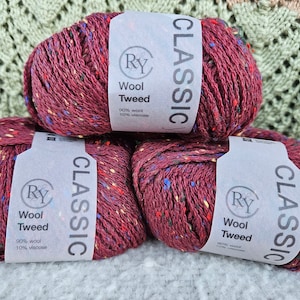 May include: Three skeins of red wool tweed yarn with a speckled pattern. Each skein has a white label with the text "CLASSIC" and "Ry Wool Tweed 90% wool 10% viscose".