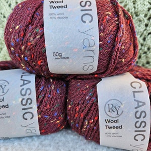 May include: Two skeins of burgundy wool tweed yarn with flecks of red, blue, green, and yellow. The yarn is labeled "Classic Yarns Wool Tweed 90% wool 10% viscose 50g 114m/125yds."