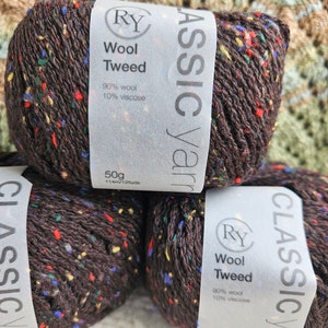 May include: Three balls of brown yarn with colorful flecks. The yarn is labeled "Classic Yarn" and "Wool Tweed" with the composition of 90% wool and 10% viscose. Each ball weighs 50 grams and contains 114 meters or 125 yards of yarn.