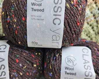 Può includere: Tre gomitoli di filato marrone con macchie colorate. Il filato è etichettato "Classic Yarn" e "Wool Tweed" con una composizione del 90% di lana e del 10% di viscosa. Ogni gomitolo pesa 50 grammi e contiene 114 metri o 125 yard di filato.