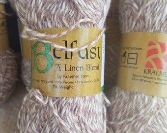 Può includere: Un gomitolo di filato marrone e bianco etichettato "Belfast A Linen Blend by Kraemer Yarns". L'etichetta include anche la composizione del filato: 22% Lino, 20% Viscosa, 11% Acrilico, 5% Seta. Il filato è etichettato come peso DK.