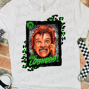 May include: A white t-shirt with a black and white graphic of a man with a shocked expression. The graphic is surrounded by a black frame and green spiderwebs. The text "Wow! Cobwebs!" is written in green letters below the graphic.