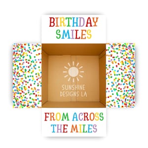 May include: An open cardboard box with colorful confetti on the sides. The top of the box reads "BIRTHDAY SMILES" in rainbow colors. The bottom of the box reads "FROM ACROSS THE MILES" in rainbow colors.