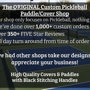 May include: A green pickleball court with a sign that reads "The ORIGINAL Custom Pickleball Paddle/Cover Shop". The sign also lists the shop's services, including over 1,000 custom orders and 350+ five-star reviews.