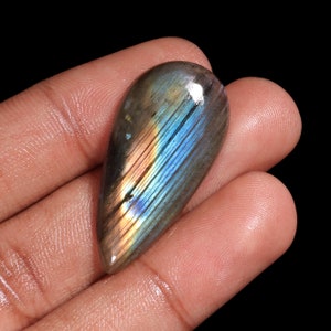 May include: A teardrop-shaped labradorite gemstone with iridescent blue, green, and gold colors.
