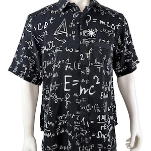 Può includere: Camicia nera a maniche corte con equazioni e simboli matematici bianchi. La camicia, esposta su un manichino, ha una tasca sul petto sinistro. Un design unico e accattivante.