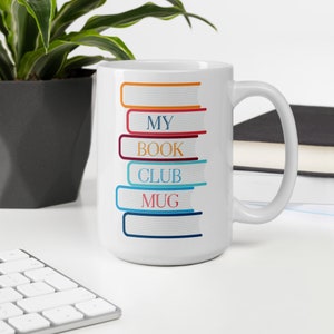 May include: White ceramic mug with a stack of colorful books printed on the side. The books have the words "My Book Club Mug" printed on them.