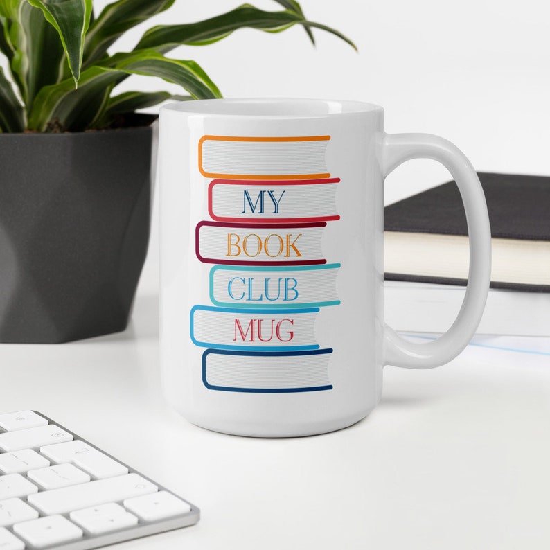 May include: White ceramic mug with a stack of colorful books printed on the side. The books have the words "My Book Club Mug" printed on them.