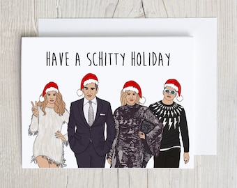 Puede incluir: Una tarjeta blanca con el texto "HAVE A SCHITTY HOLIDAY" en letras negras. La tarjeta presenta una ilustración de dibujos animados de cuatro personas con gorros de Papá Noel. Las personas están de pie en fila y todas sonríen.