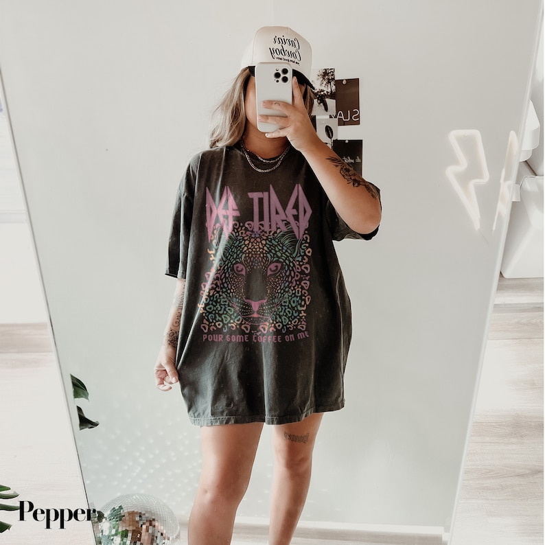 Puede incluir: Una camiseta gris oscura de gran tama&ntilde;o con un estampado de leopardo colorido y el texto "Get Tired Pour Some Coffee On Me".