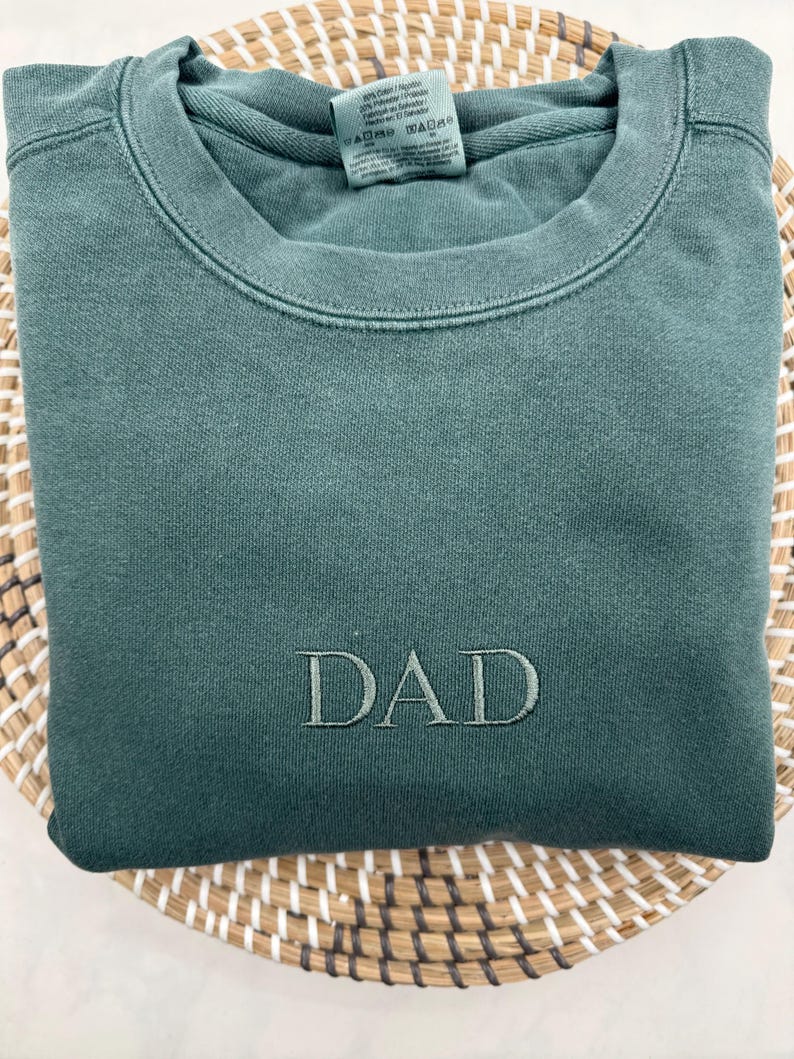 May include: A dark green sweatshirt with the word "DAD" embroidered on the front.