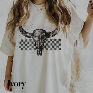 a woman wearing a white shirt with a cow skull on it