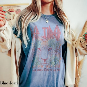 Puede incluir: Una camiseta azul con un gr&aacute;fico de la cara de un leopardo y el texto "Retired. Pour some coffee on me."