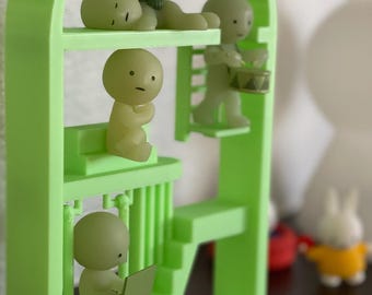 May include: A green plastic structure with four small, glowing, white figures inside. The figures are in different poses, including sleeping, sitting, and playing a drum.
