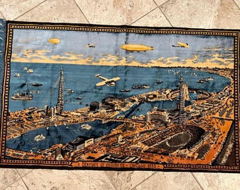 May include: A rectangular woven tapestry featuring a panoramic view of the 1933 Chicago World's Fair. The scene depicts blue water, tall towers, airplanes, and airships in yellow and blue tones. The text A CENTURY OF PROGRESS CHICAGO 1933 is visible.