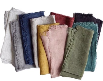 May include: Set of ten linen napkins in various colors, including gray, blue, yellow, pink, green, and teal. The napkins have a frayed edge and are folded in a stack.