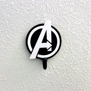 May include: A black and white Avengers logo with a hook on the bottom. The logo is a stylized letter "A" with an arrow pointing to the right.