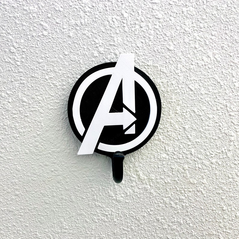 May include: A black and white Avengers logo with a hook on the bottom. The logo is a stylized letter "A" with an arrow pointing to the right.