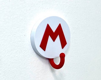 May include: White wall hook with a red "M" and a red hook. The hook is shaped like a question mark.