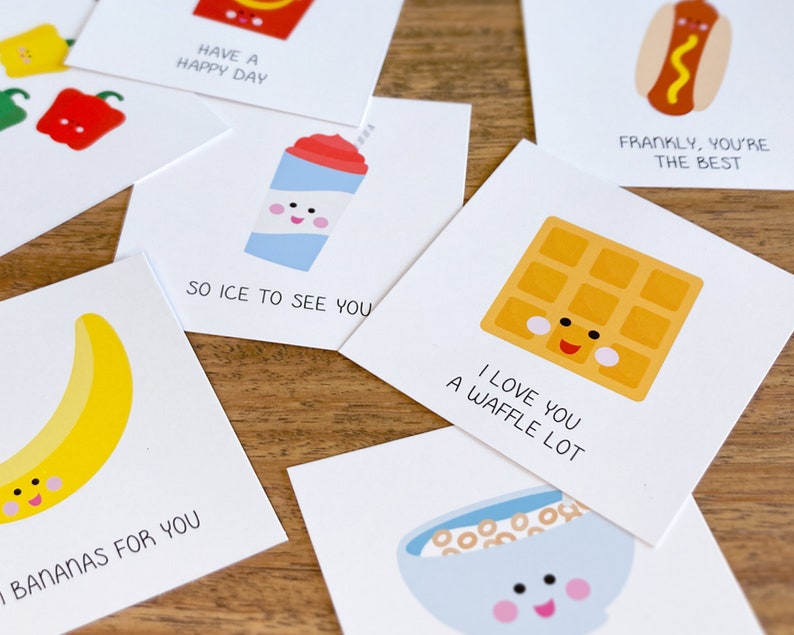 May include: A set of ten greeting cards with cute food illustrations and puns. The cards are white with black text and feature a banana, a waffle, a hot dog, a slushie, a bowl of cereal, and a red pepper.
