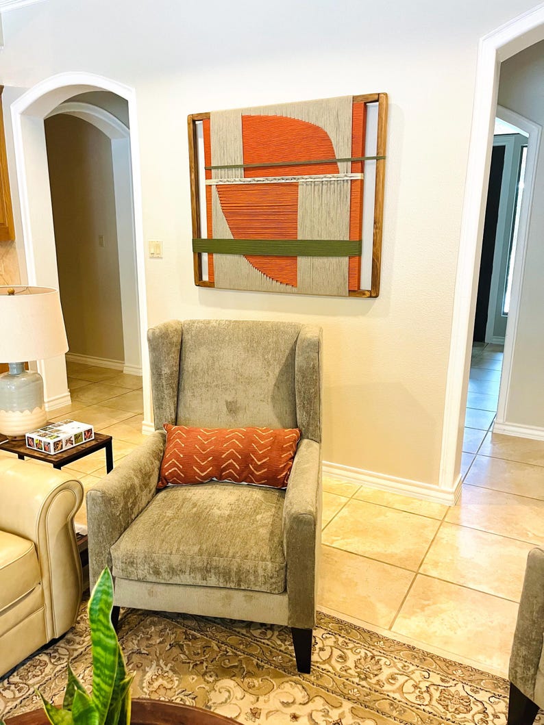 a cozy living room with a beige armchair, a wooden coffee table, and a large abstract painting on the wall.