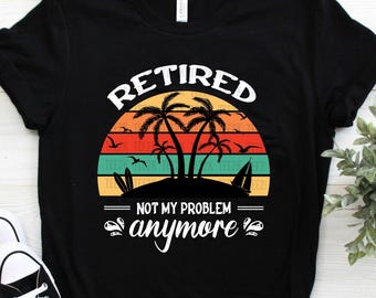 以下が含まれることがあります： 「RETIRED NOT MY PROBLEM anymore」というテキストとレトロな夕焼けのグラフィックが描かれた黒いTシャツ。