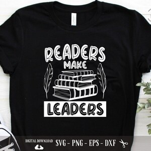 Könnte beinhalten: Schwarzes T-Shirt mit weißem Text, der "Readers Make Leaders" lautet, und einer Grafik eines Bücherstapels mit einer Feder auf jeder Seite.