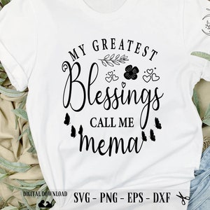May include: White t-shirt with black text that reads "My Greatest Blessings Call Me Mema". The text is surrounded by small black flowers, hearts, and butterflies.