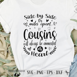 Puede incluir: Camiseta blanca con texto negro que dice "Side by Side Or miles apart Cousins will always be connected By Heart". El texto está rodeado de corazones, estrellas y diseños florales.