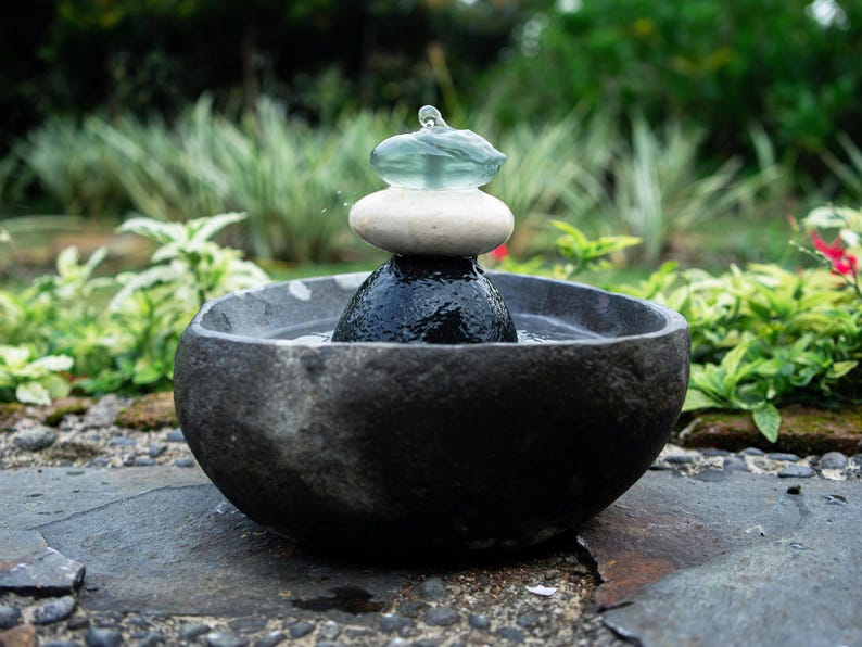 Handcrafted Zen Balance Cairns Fountain with a carved natural river stone base, stacked cairn of river stone, white jasper, and recycled aqua glass top. Creates soothing water flow and relaxing sound, ideal for meditation, relaxation, or mindful home décor. Includes 6 ft cord low-voltage pump with adjustable flow. Perfect for indoor use or covered patios, adding a calming focal point to gardens, desks, or living spaces. Unique, nature-inspired gift for spa lovers and meditation spaces.