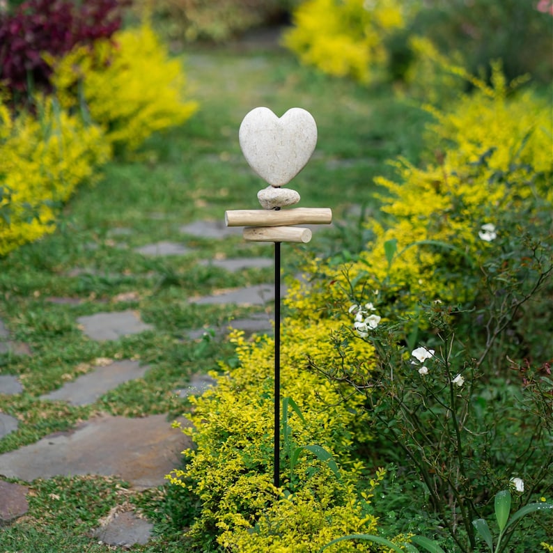Hand-carved Jasper Stone Heart Harmony Garden Stake featuring a smooth heart shape paired with rustic driftwood on a sturdy metal pole. Each heart is individually carved by hand from genuine Jasper stone, symbolizing love, healing, and grounding energy. A meaningful accent for gardens, memorials, or weddings—this natural outdoor decor piece adds warmth, artistry, and heartfelt charm to any space.