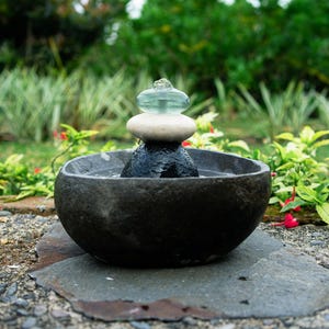 Handcrafted Zen Balance Cairns Fountain with a carved natural river stone base, stacked cairn of river stone, white jasper, and recycled aqua glass top. Creates soothing water flow and relaxing sound, ideal for meditation, relaxation, or mindful home décor. Includes 6 ft cord low-voltage pump with adjustable flow. Perfect for indoor use or covered patios, adding a calming focal point to gardens, desks, or living spaces. Unique, nature-inspired gift for spa lovers and meditation spaces.