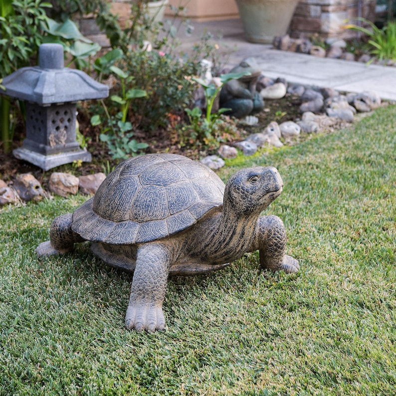 Realistic fiber cement turtle statue available in two sizes, small 14 inch and huge 34 inch life size. Handcrafted with intricate details, the design resembles a sea turtle or tortoise with a textured shell and natural stone-like finish. Perfect for outdoor display in gardens, patios, entryways, or zen spaces, this rustic sculpture is durable, weather resistant, and eco-friendly. A striking yard art figurine and unique gift for turtle lovers and garden enthusiasts.