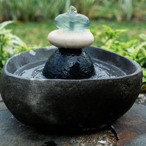 Handcrafted Zen Balance Cairns Fountain with a carved natural river stone base, stacked cairn of river stone, white jasper, and recycled aqua glass top. Creates soothing water flow and relaxing sound, ideal for meditation, relaxation, or mindful home décor. Includes 6 ft cord low-voltage pump with adjustable flow. Perfect for indoor use or covered patios, adding a calming focal point to gardens, desks, or living spaces. Unique, nature-inspired gift for spa lovers and meditation spaces.