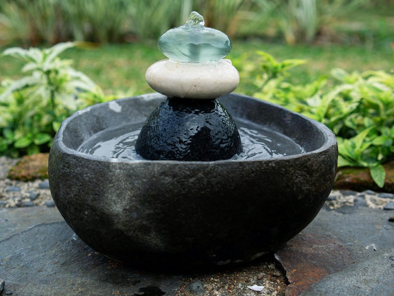 Handcrafted Zen Balance Cairns Fountain with a carved natural river stone base, stacked cairn of river stone, white jasper, and recycled aqua glass top. Creates soothing water flow and relaxing sound, ideal for meditation, relaxation, or mindful home décor. Includes 6 ft cord low-voltage pump with adjustable flow. Perfect for indoor use or covered patios, adding a calming focal point to gardens, desks, or living spaces. Unique, nature-inspired gift for spa lovers and meditation spaces.