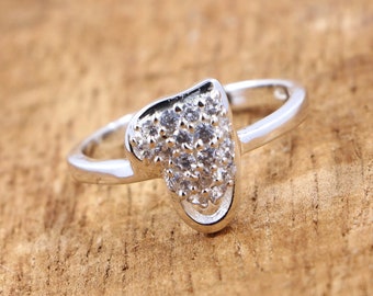 May include: A silver ring with a heart-shaped design. The heart is covered in small, clear cubic zirconia stones.
