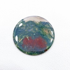Peut inclure: Un cabochon rond en agate de couleur verte, rouge et blanche avec une surface polie. La pierre présente un motif tourbillonnant de couleurs.