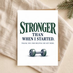 May include: A white greeting card featuring the dark green text STRONGER, followed by the dark blue text THAN WHEN I STARTED. Below this is the text THANK YOU FOR HELPING ME GET HERE, and a detailed illustration of a grey and green dumbbell.