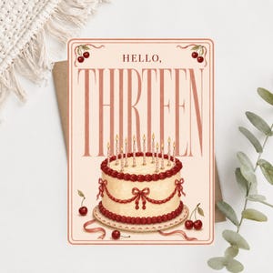 May include: A rectangular greeting card with a cream background featuring the text HELLO, THIRTEEN in large brown letters. Below the text is a white cake with red piped frosting, bows, and ten lit candles. Red cherries decorate the corners and base.