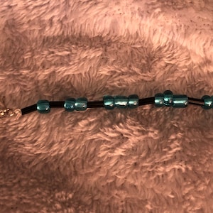 May include: A black beaded bracelet with a silver clasp and turquoise blue beads.