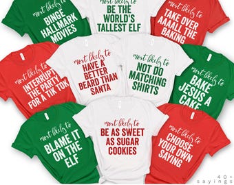 May include: A collection of t-shirts in red, green, and white, each with a different humorous phrase in a bold font. Phrases include "Binge Hallmark Movies," "Be the World's Tallest Elf," and "Choose Your Own Saying." The shirts are part of "The Original Collection."